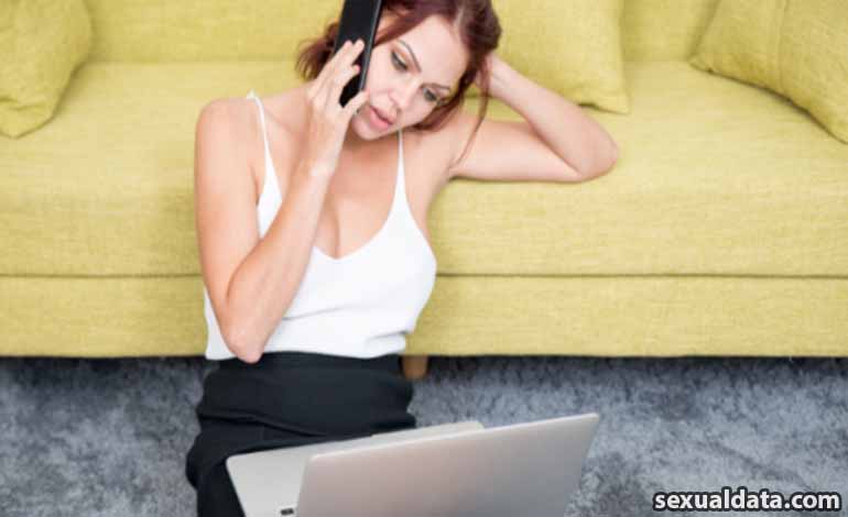 Adult Men Toys Comparison: How to Find the Right Fit for You Woman sitting on a yellow sofa, talking on a smartphone with a laptop on the floor nearby.